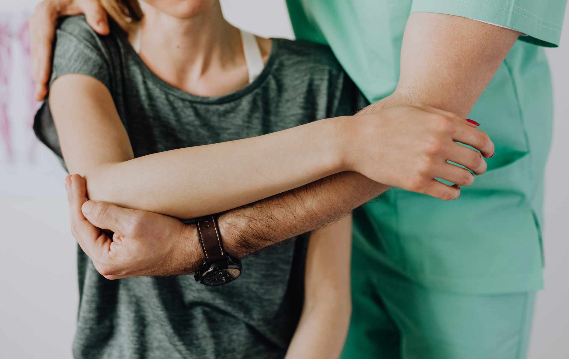 A healthcare worker supports a person's arm, assessing their elbow's mobility.