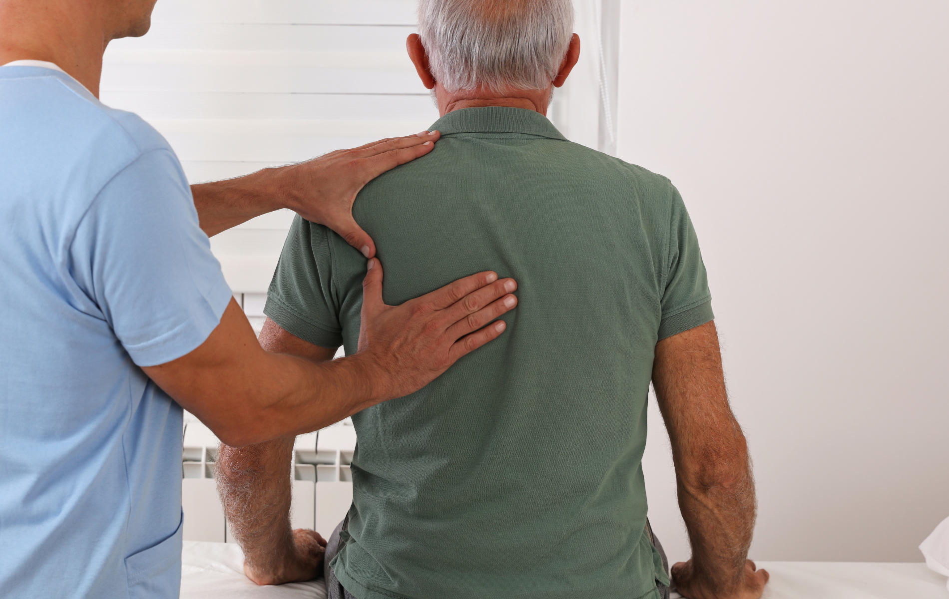 Healthcare worker examines patient's back.