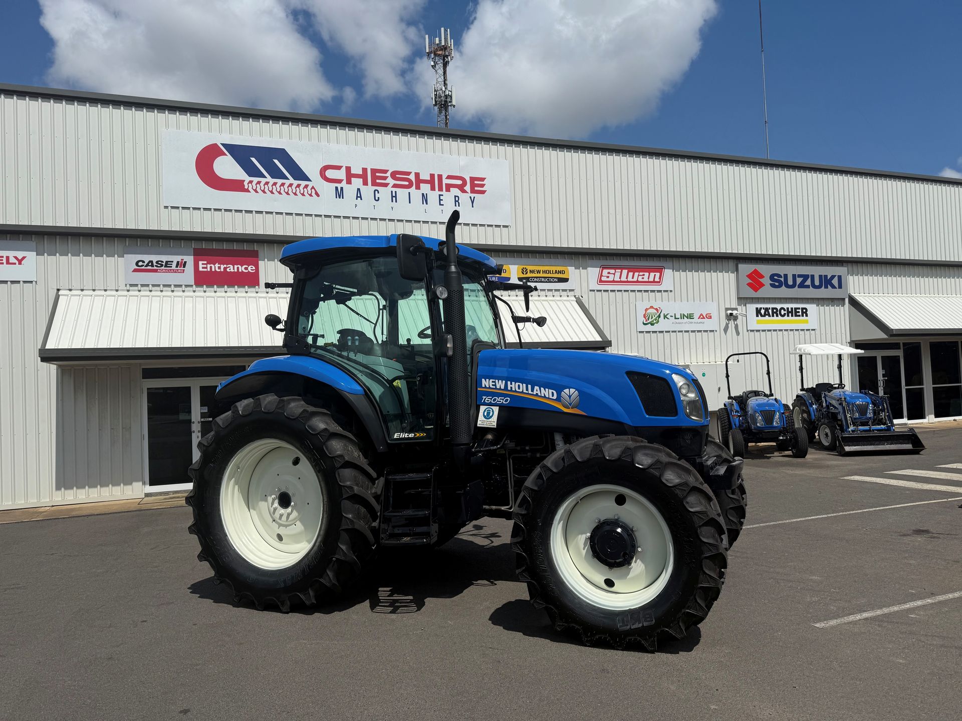 A john deere tractor is parked in front of a cheshire machinery store