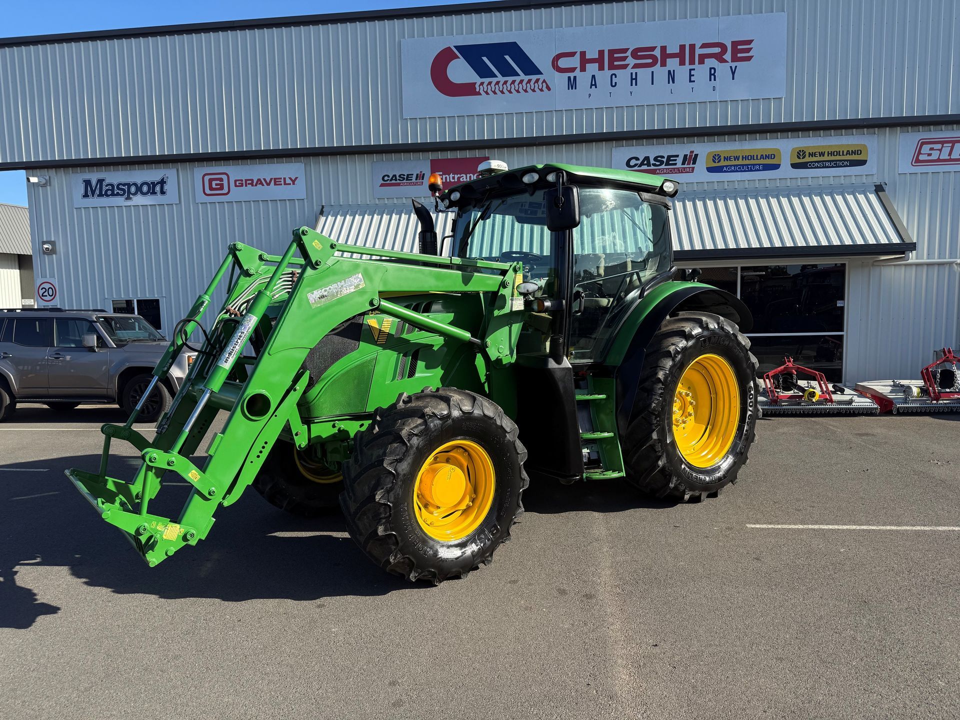 A John Deere Tractor is Parked in Front of a Building — Cheshire Machinery in Murgon, QLD