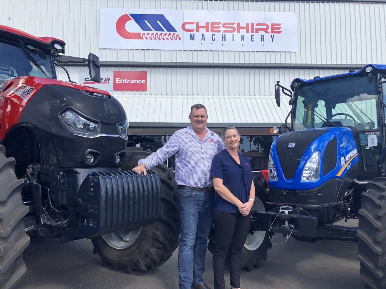 Two Owners standing next to Two Tractors Parked in Front of A Building — Cheshire Machinery in Svensson Heights, QLD