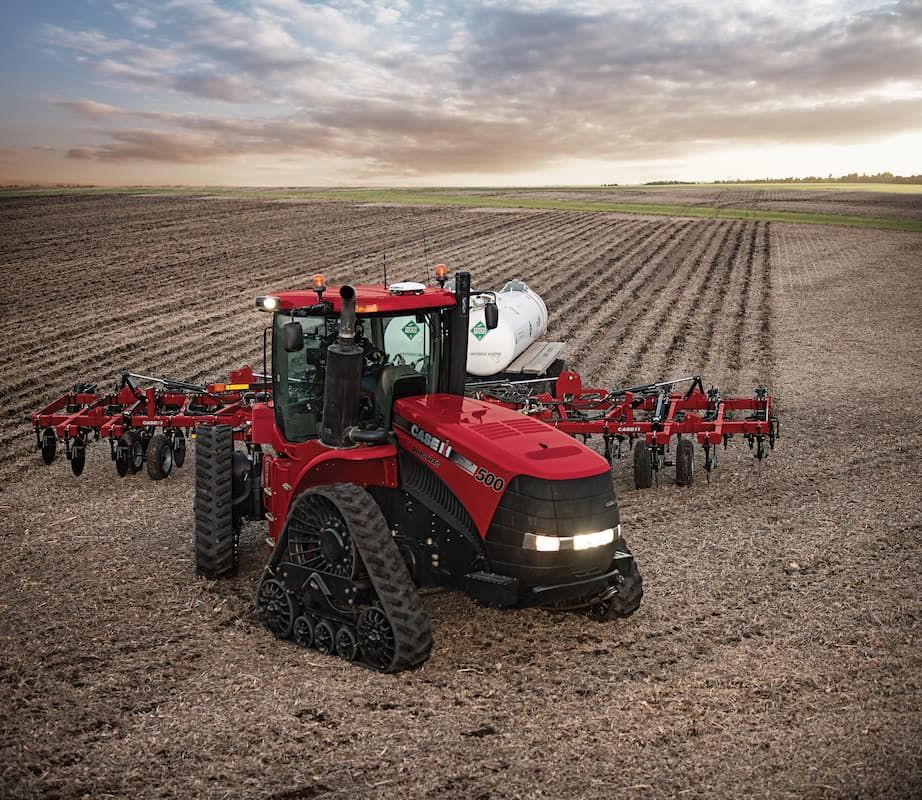 A Red Tractor Is Plowing a Field with A Plow Attached to It — Cheshire Machinery in Murgon, QLD