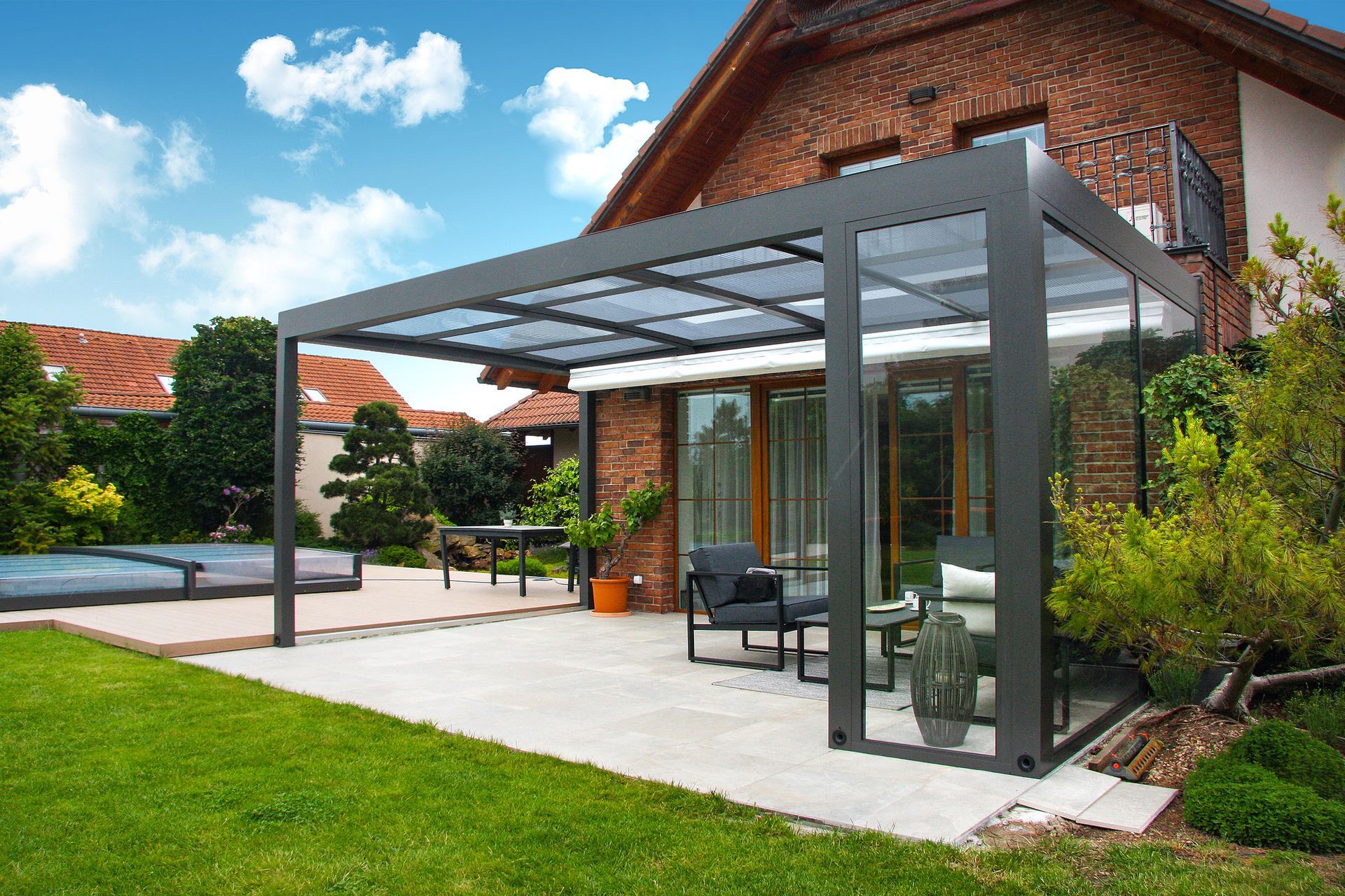 Ein Haus mit Terrasse und davor liegender Pergola.