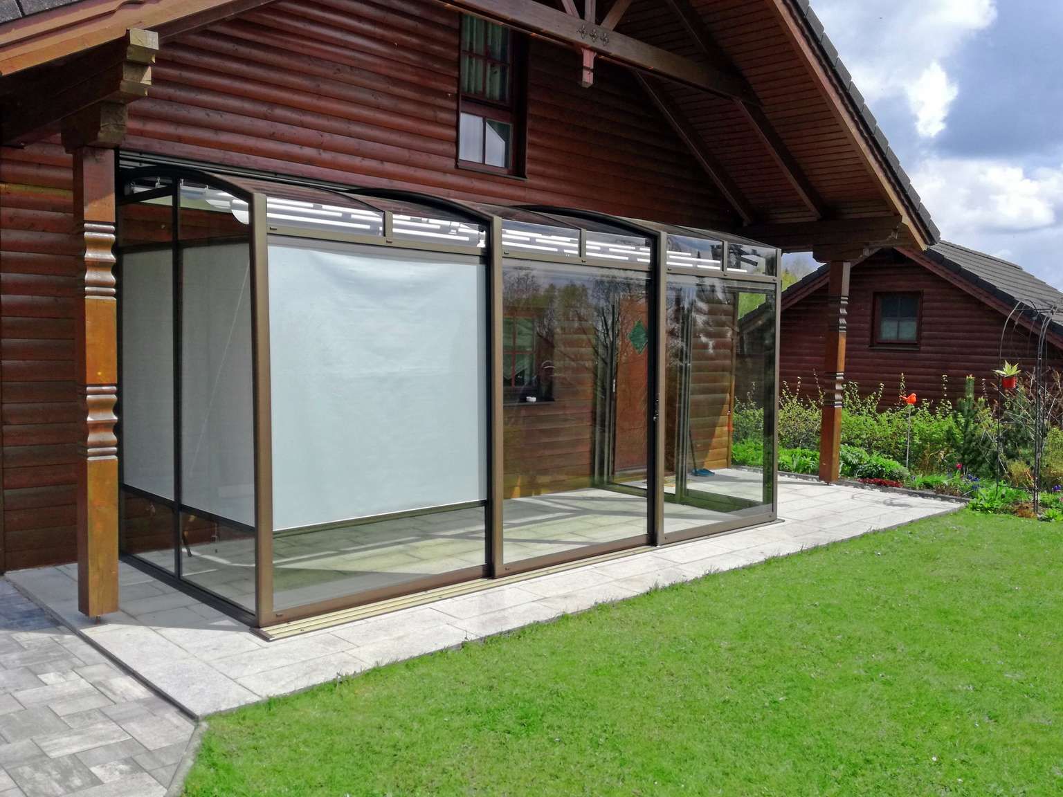 Ein Holzhaus mit einer abgeschirmten Veranda und einem Rasen davor.