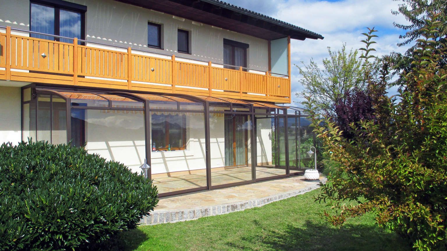 Ein Haus mit Balkon und vorgelagerter Terrasse.