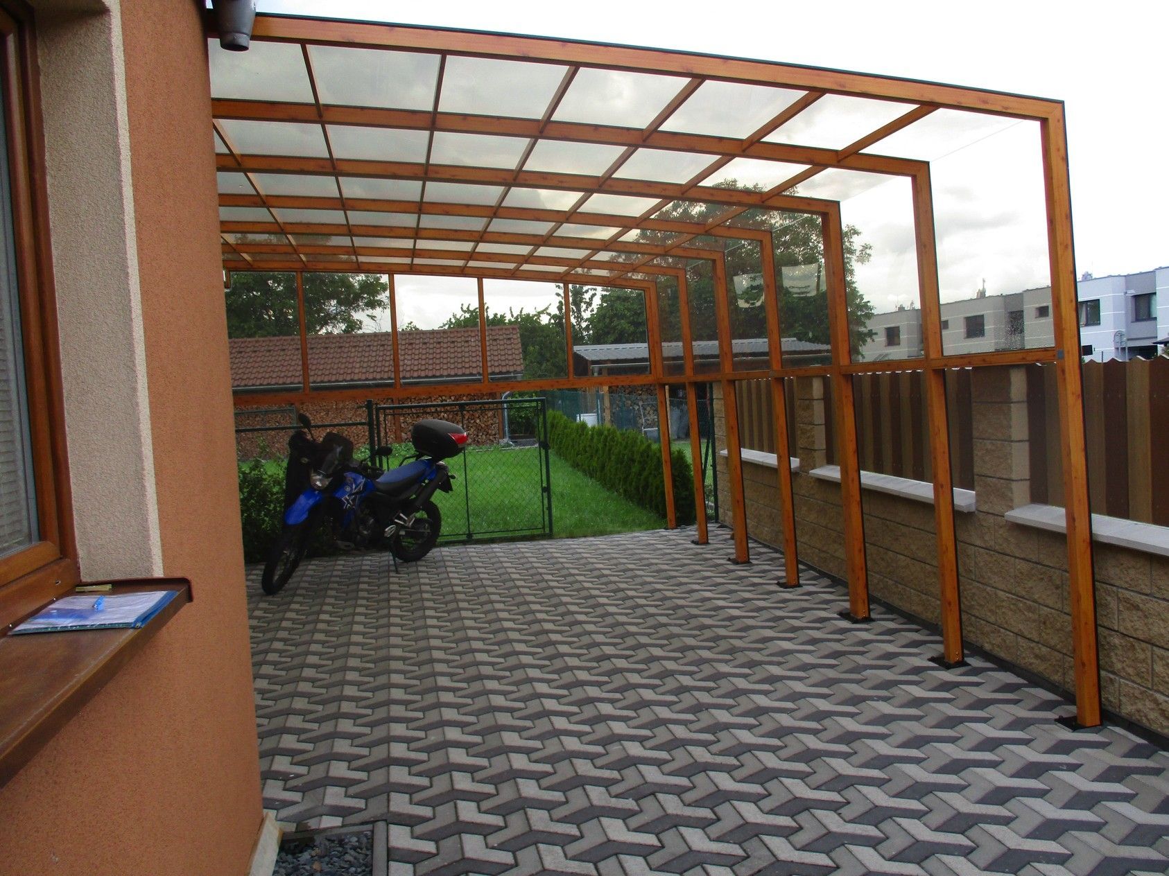 Ein Motorrad ist unter einem Vordach in einer Einfahrt geparkt