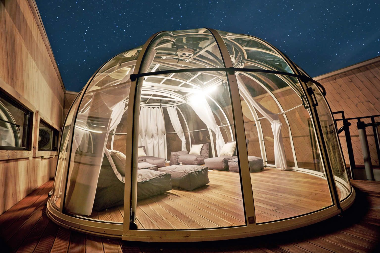 Eine Glaskuppel mit Holzboden und Stühlen darin.