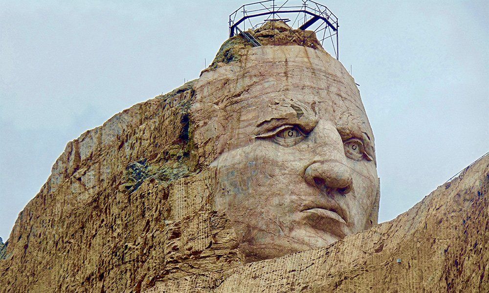 A statue of a man 's head is sitting on top of a rocky hill.