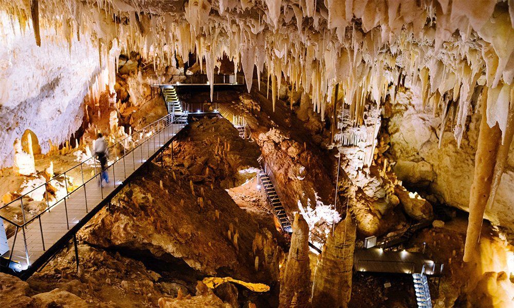 A man is walking through a cave with a bridge.