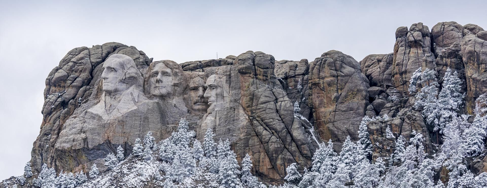 A statue of the presidents of the united states on top of a mountain covered in snow.