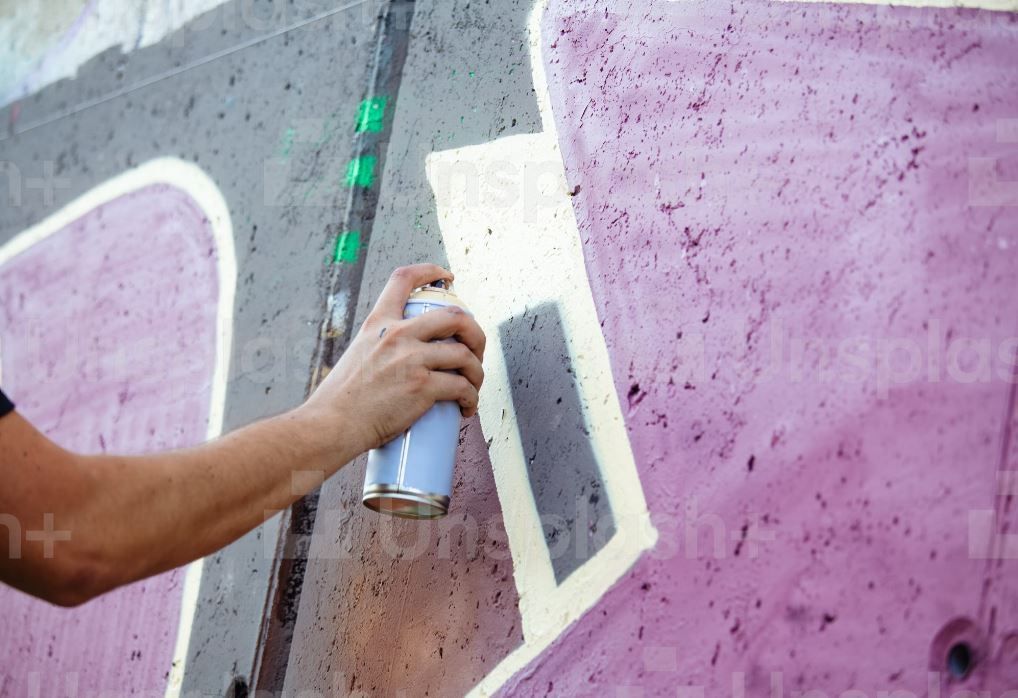 A person is spray painting graffiti on a wall.