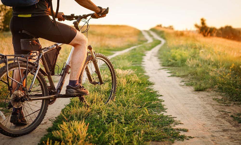 A person is riding a bike on a dirt road.