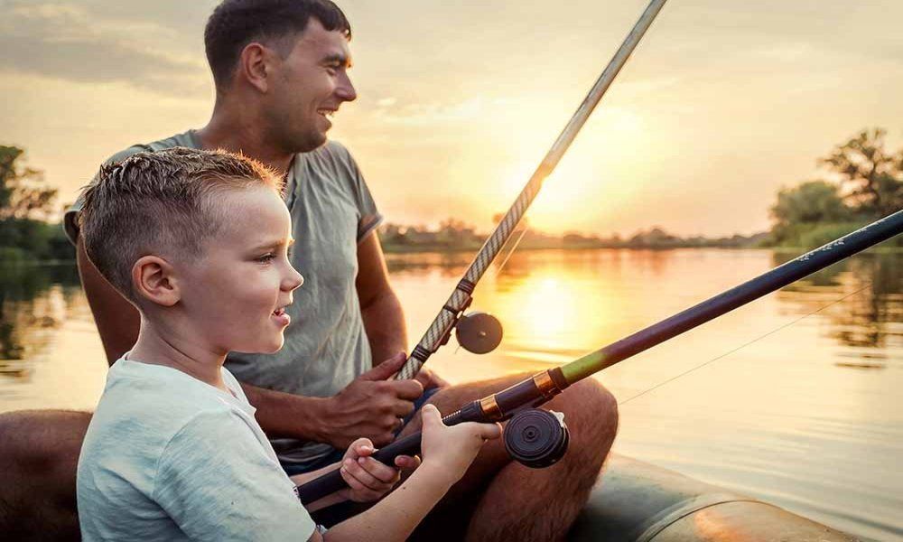 A man and a boy are fishing in a boat on a lake.