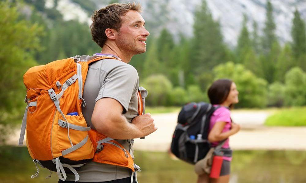 A man and a woman are hiking in the mountains with backpacks.