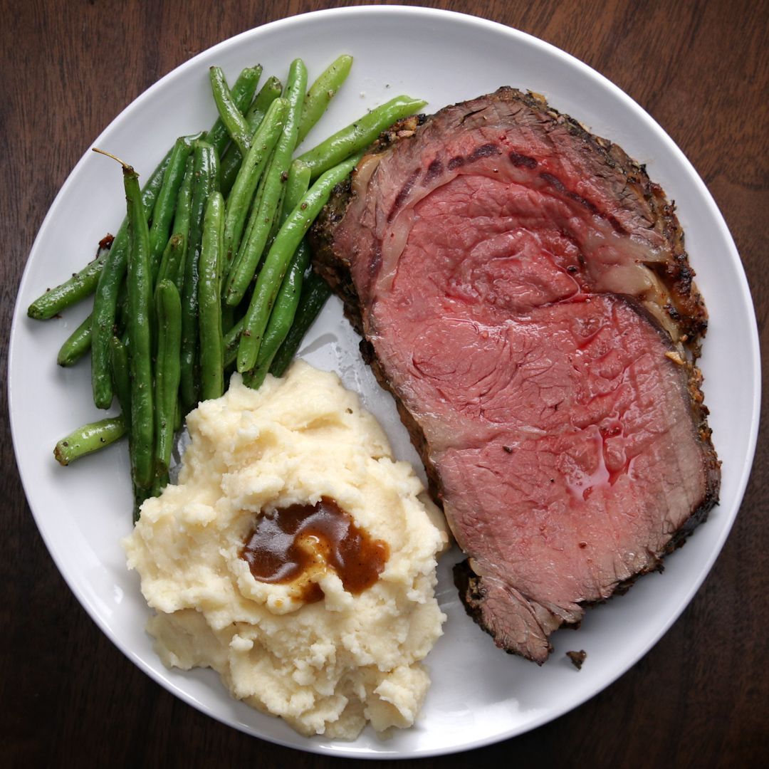 A white plate topped with meat mashed potatoes and green beans