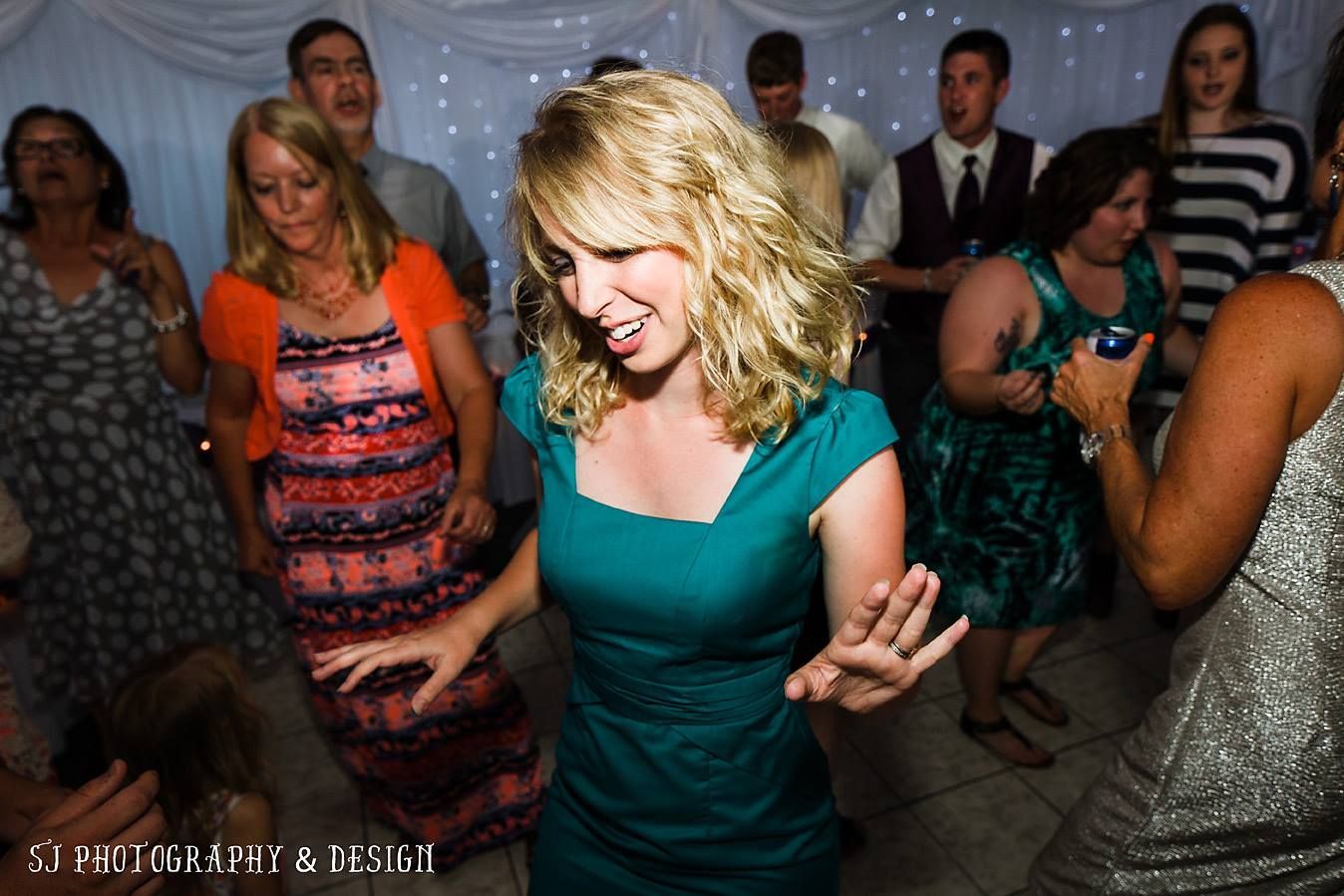 A woman in a green dress is dancing at a wedding reception