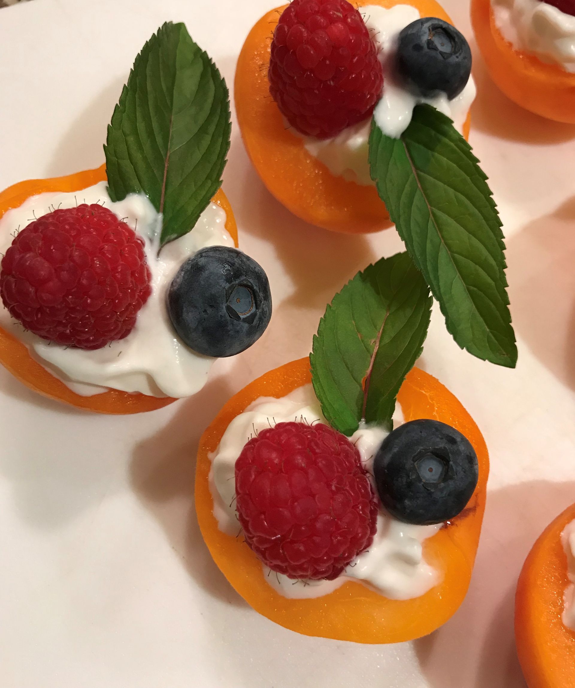 A white plate topped with oranges filled with raspberries and blueberries