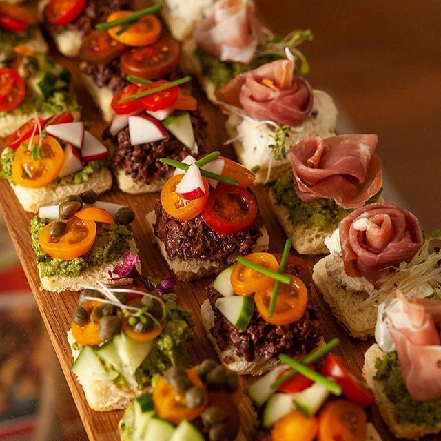 A wooden cutting board topped with a variety of appetizers