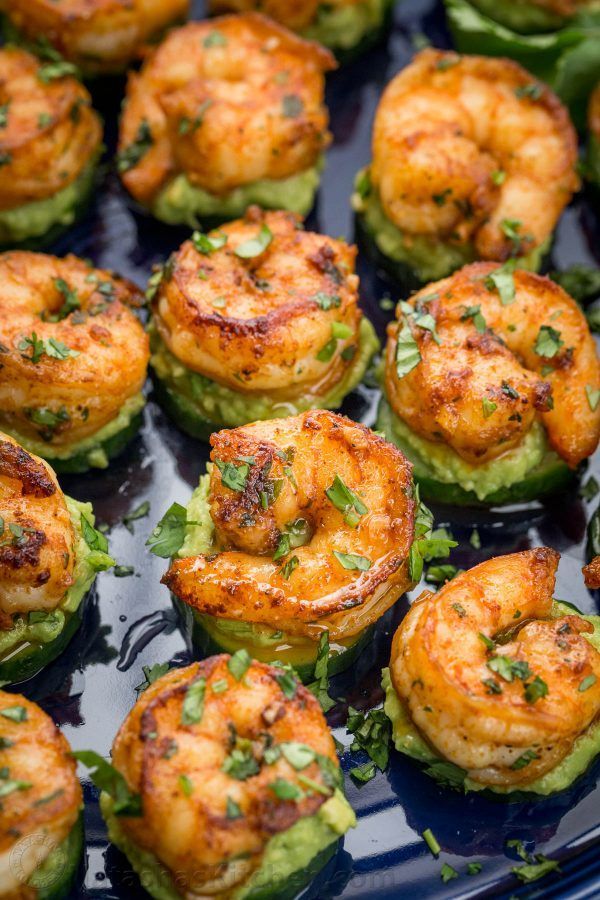 A blue plate topped with shrimp and avocado on cucumber slices.