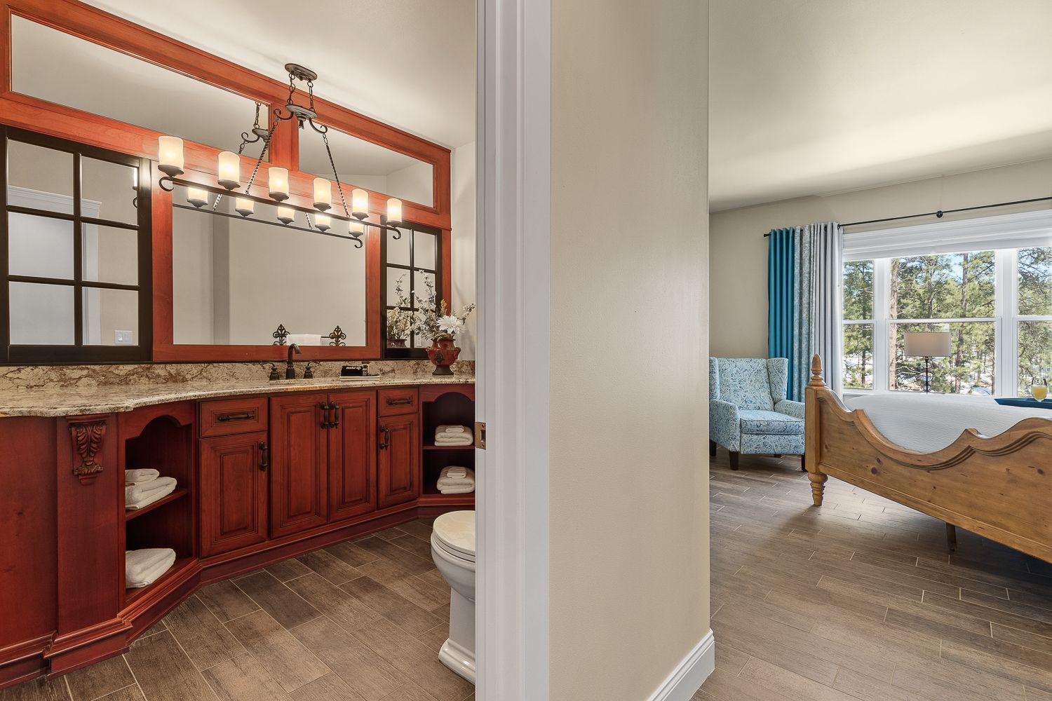 A bathroom with red cabinets , a toilet , and a large mirror.