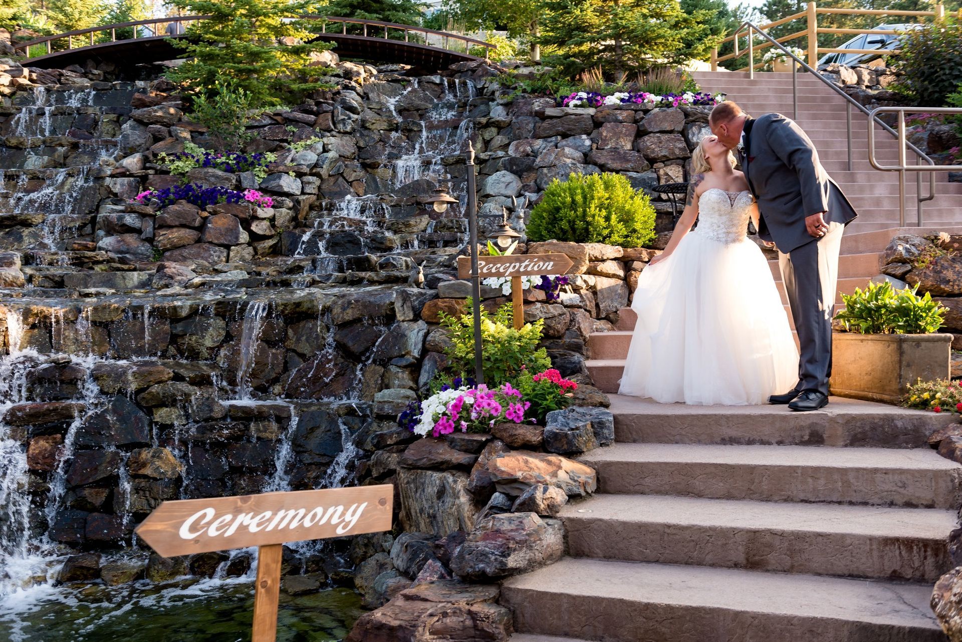 A bride and groom kissing in front of a waterfall.