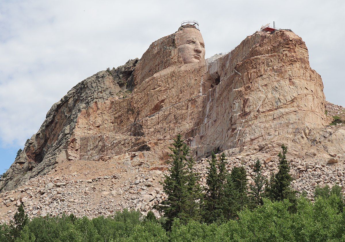 A large rock formation with a statue on top of it