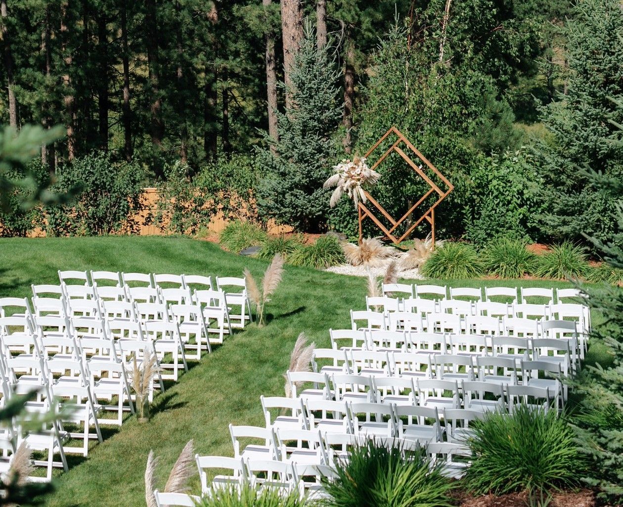 A row of white chairs are lined up in a grassy field.