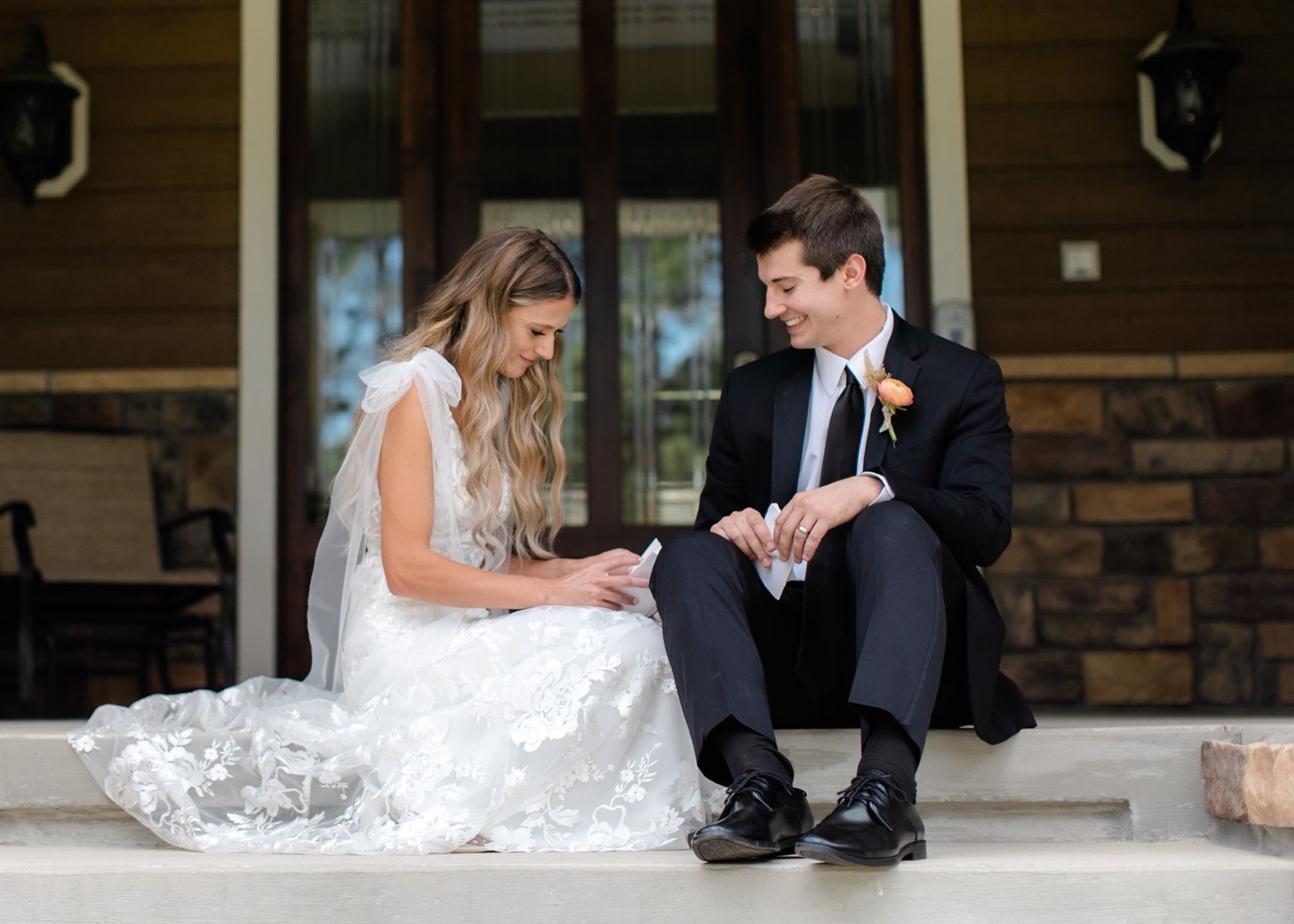 A bride and groom are sitting on the steps of a house.