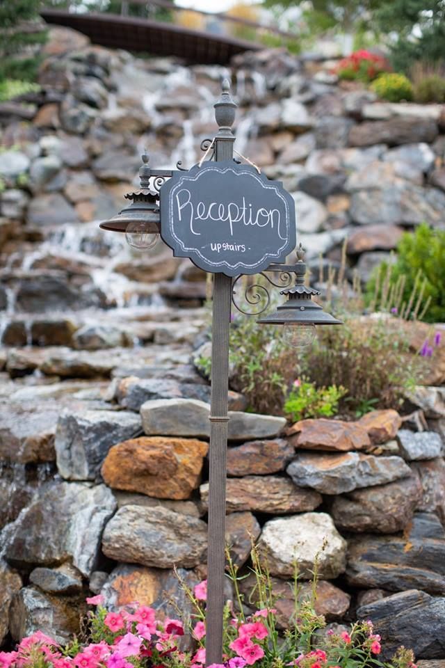 A chalkboard sign is sitting in front of a waterfall.