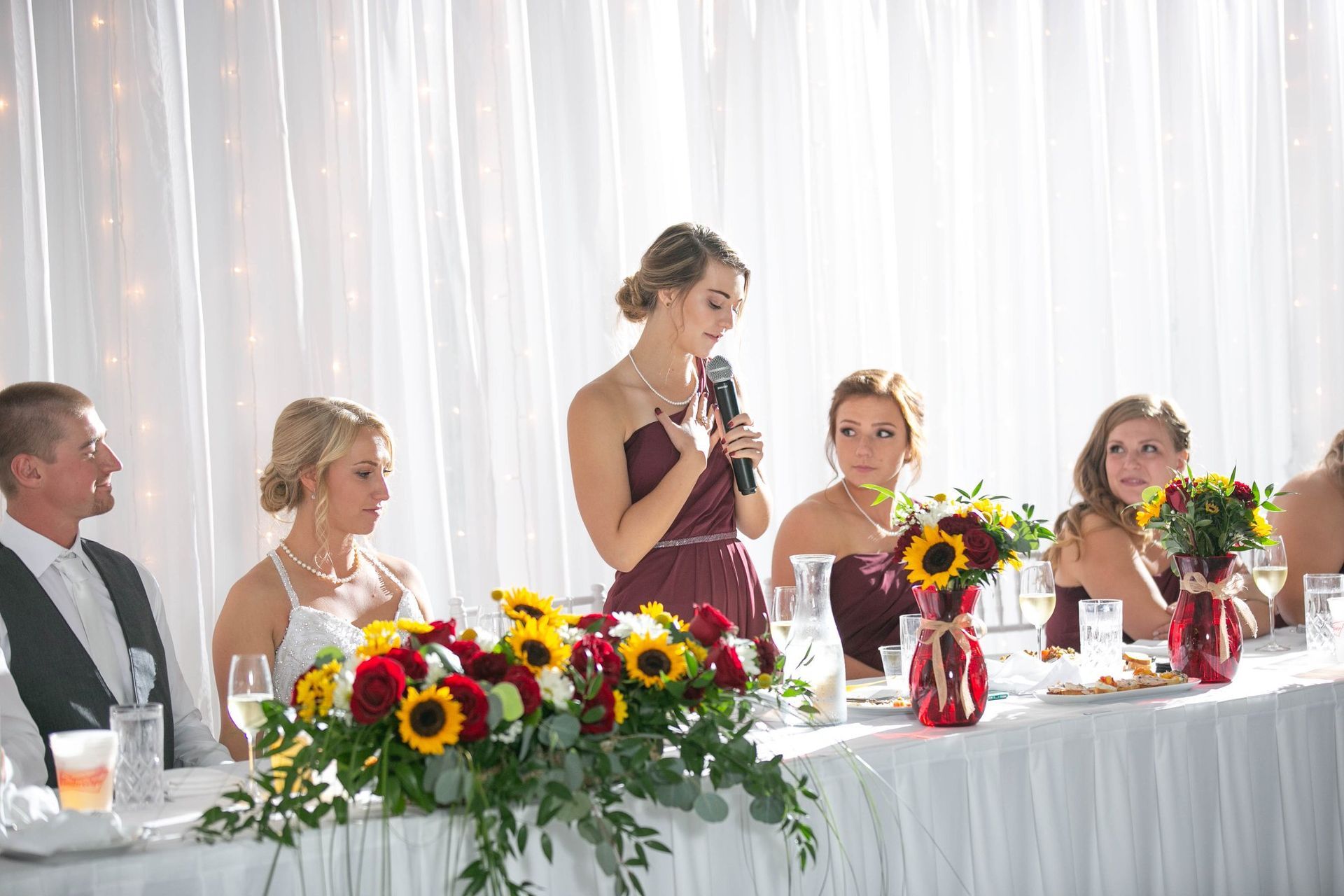 A woman is giving a speech at a wedding reception.