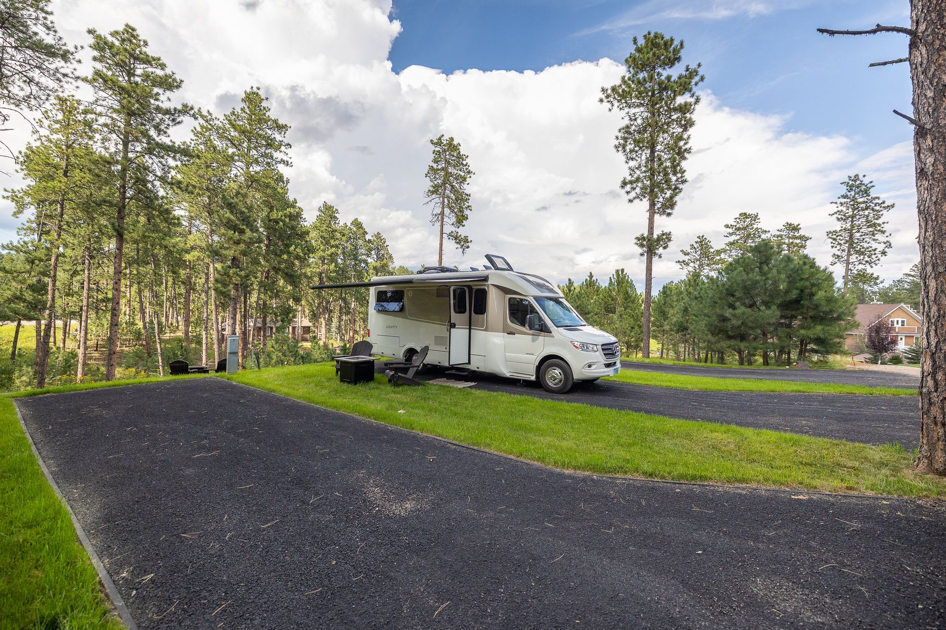 A white rv is parked in a grassy area surrounded by trees.