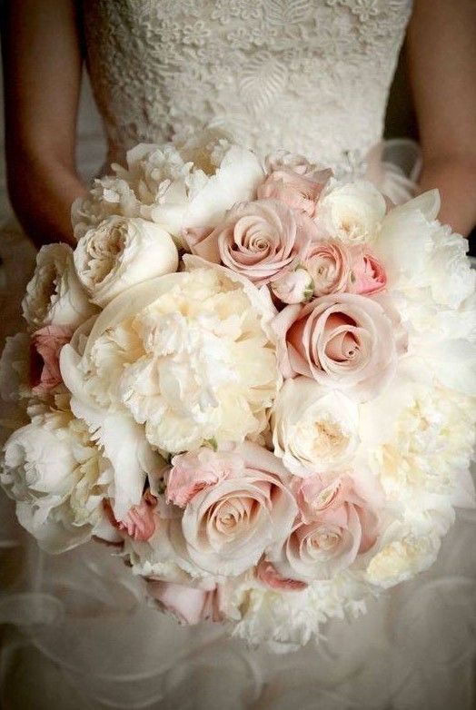 A bride in a white dress is holding a bouquet of pink and white flowers.