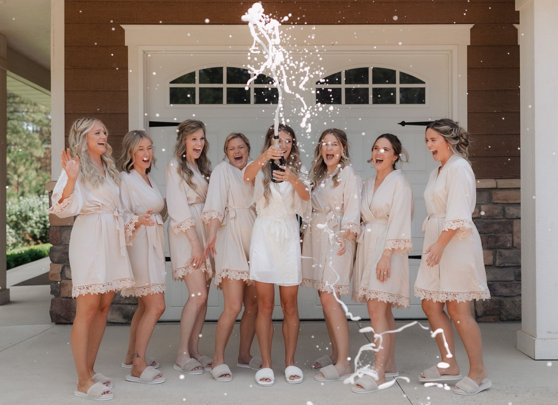 A bride and her bridesmaids are posing for a picture in front of a garage door.