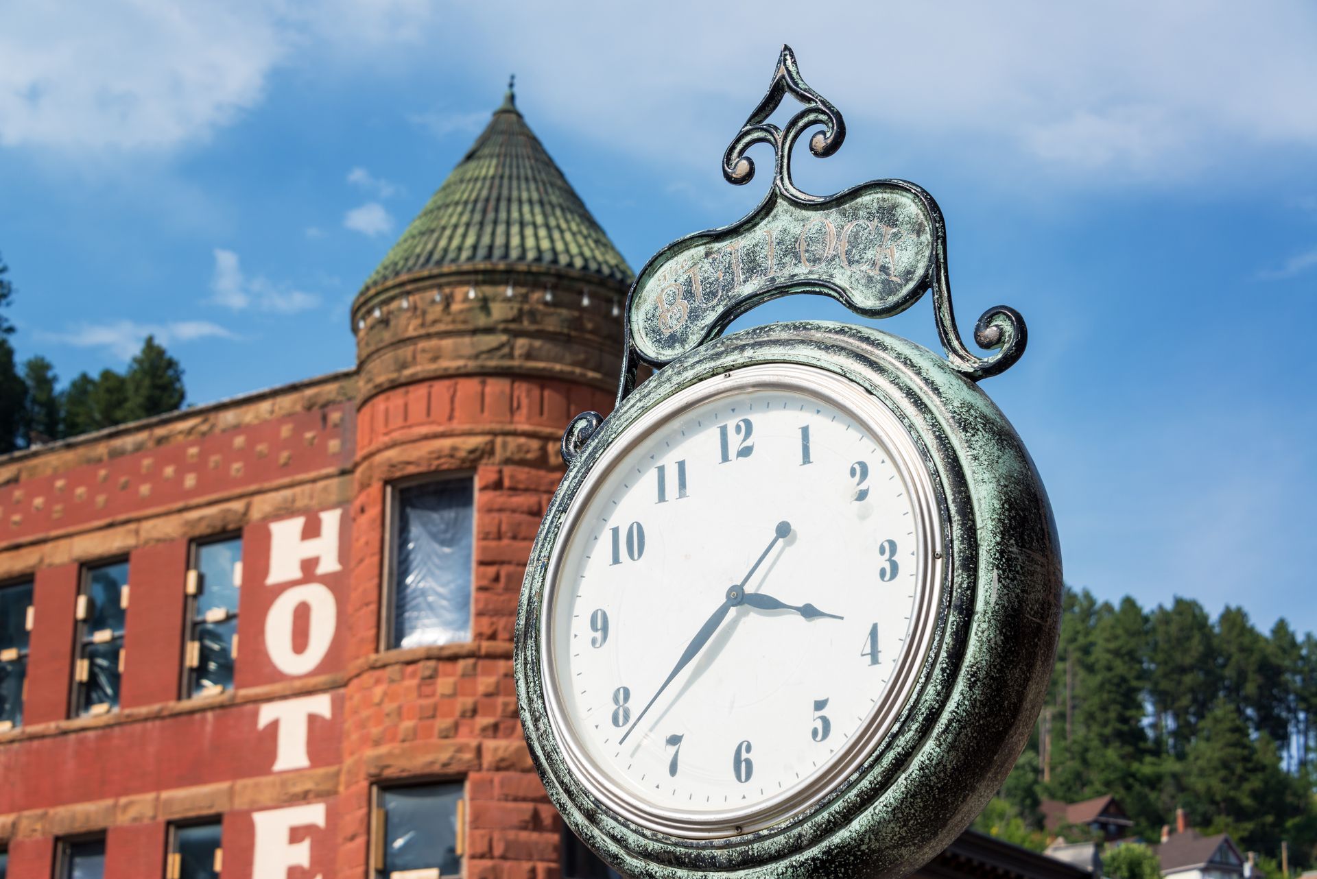 A clock in front of a building that says hotel