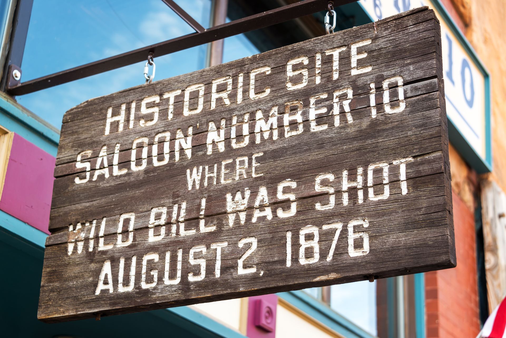 A wooden sign that says historic site saloon number 10 where wild bill was shot august 2 1876