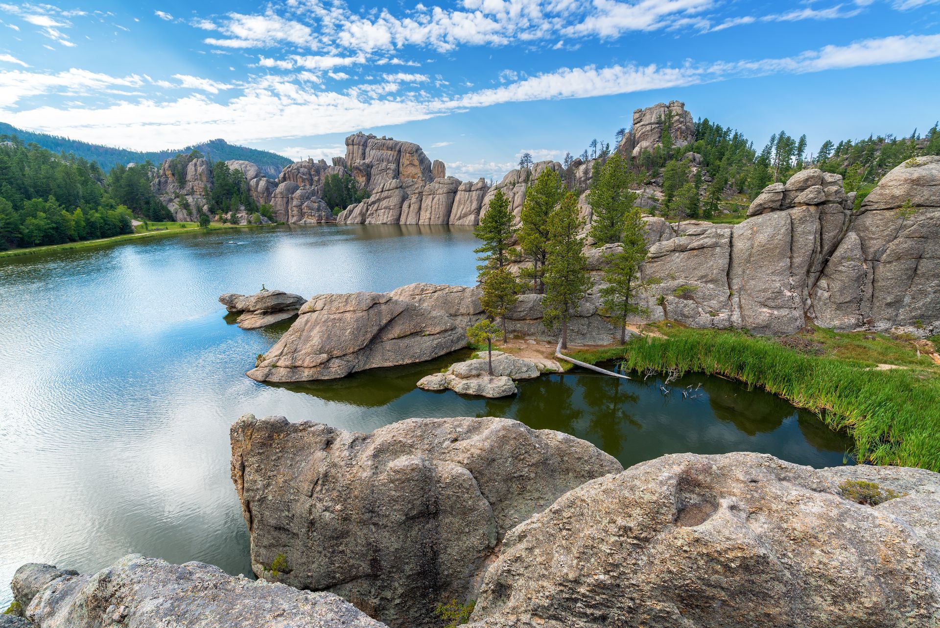 A lake surrounded by rocks and trees in the middle of a forest.