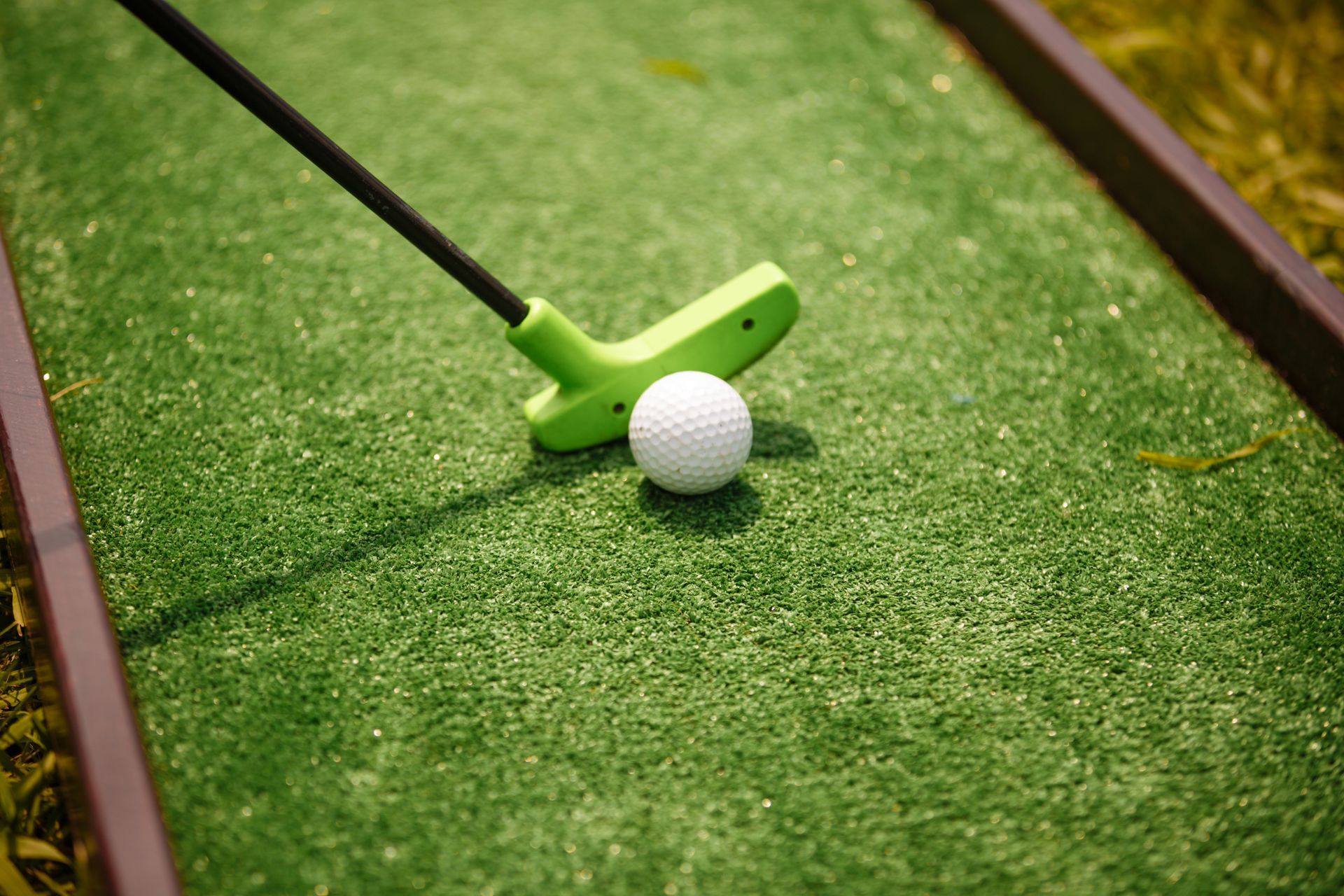 A person is playing mini golf on a green course.