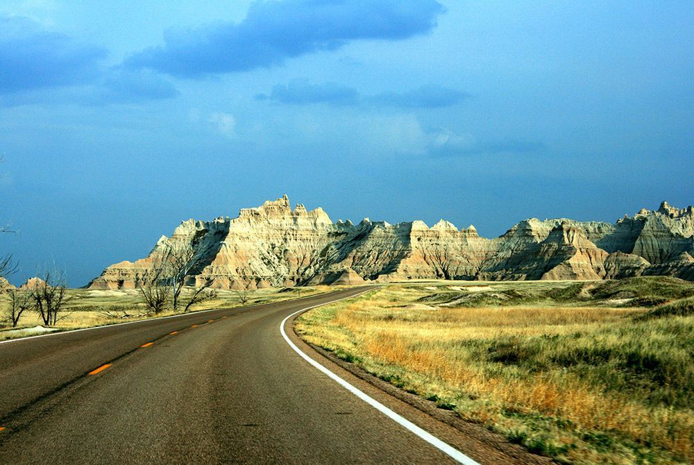 A road going through a desert with mountains in the background