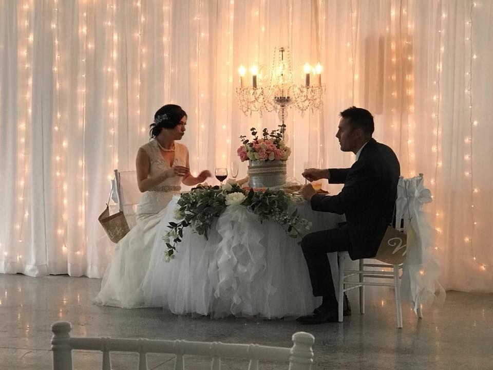 A bride and groom are sitting at a table at their wedding reception.