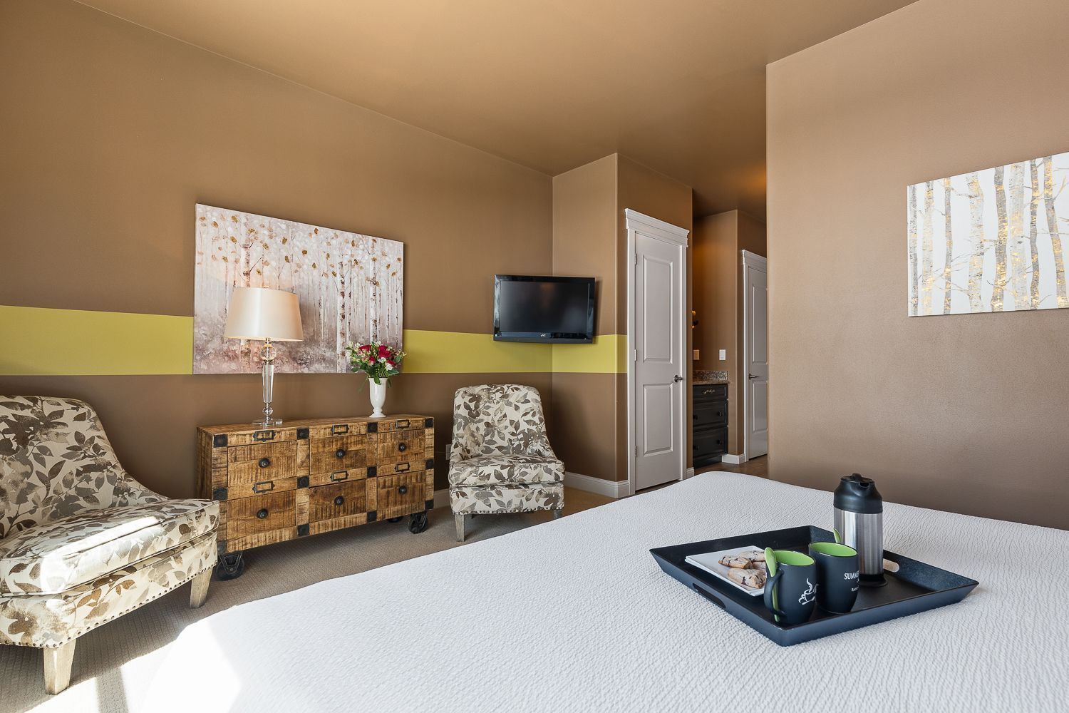 A bedroom with a bed , chairs , dresser and television.