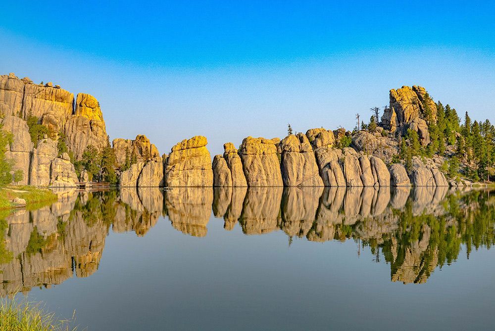A lake surrounded by rocks and trees with a reflection of the rocks in the water.
