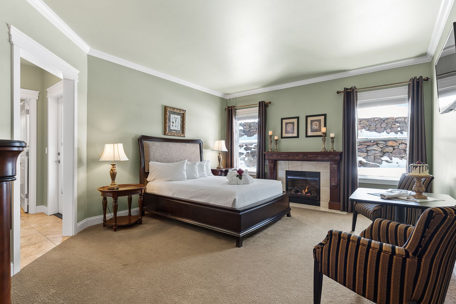 A bedroom with a bed , chair , table and fireplace.