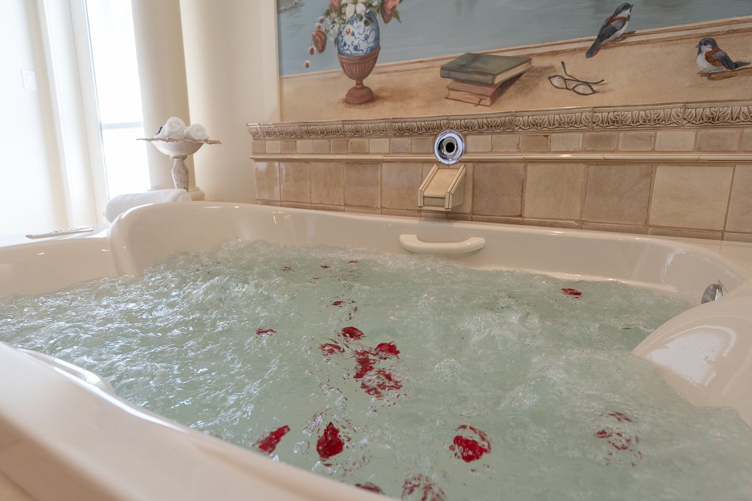 A jacuzzi tub filled with water and rose petals in a bathroom.