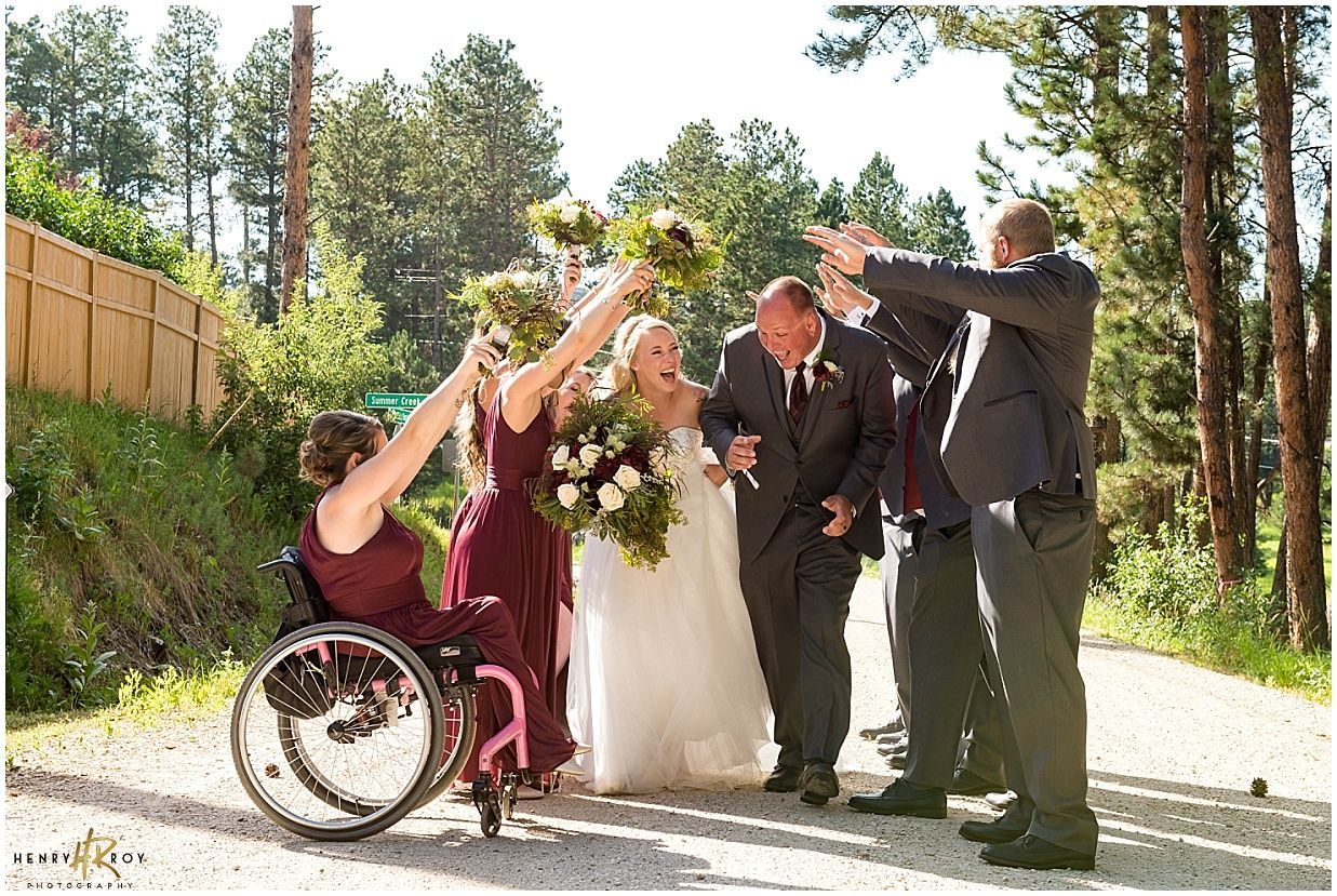 A woman in a wheelchair is standing next to a bride and groom.