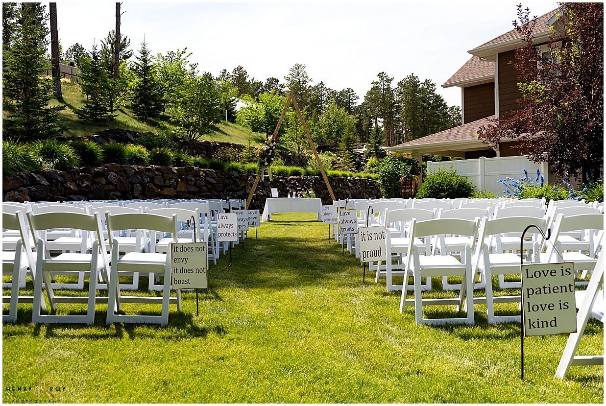 A row of white folding chairs are lined up in a grassy field