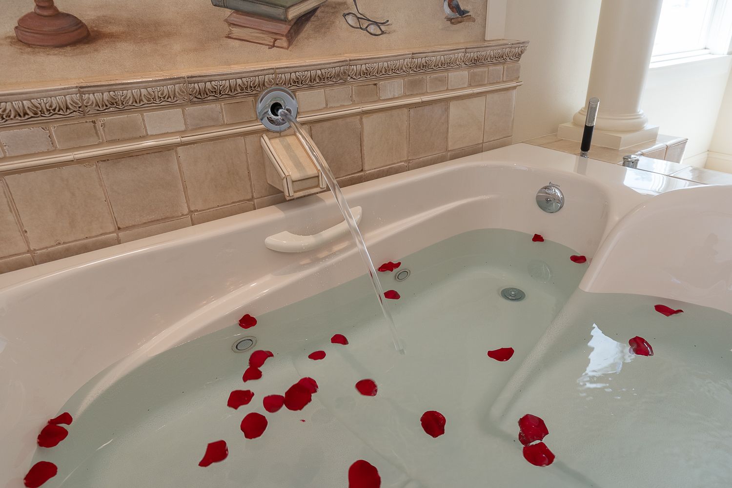 A bathtub filled with water and rose petals in a bathroom.