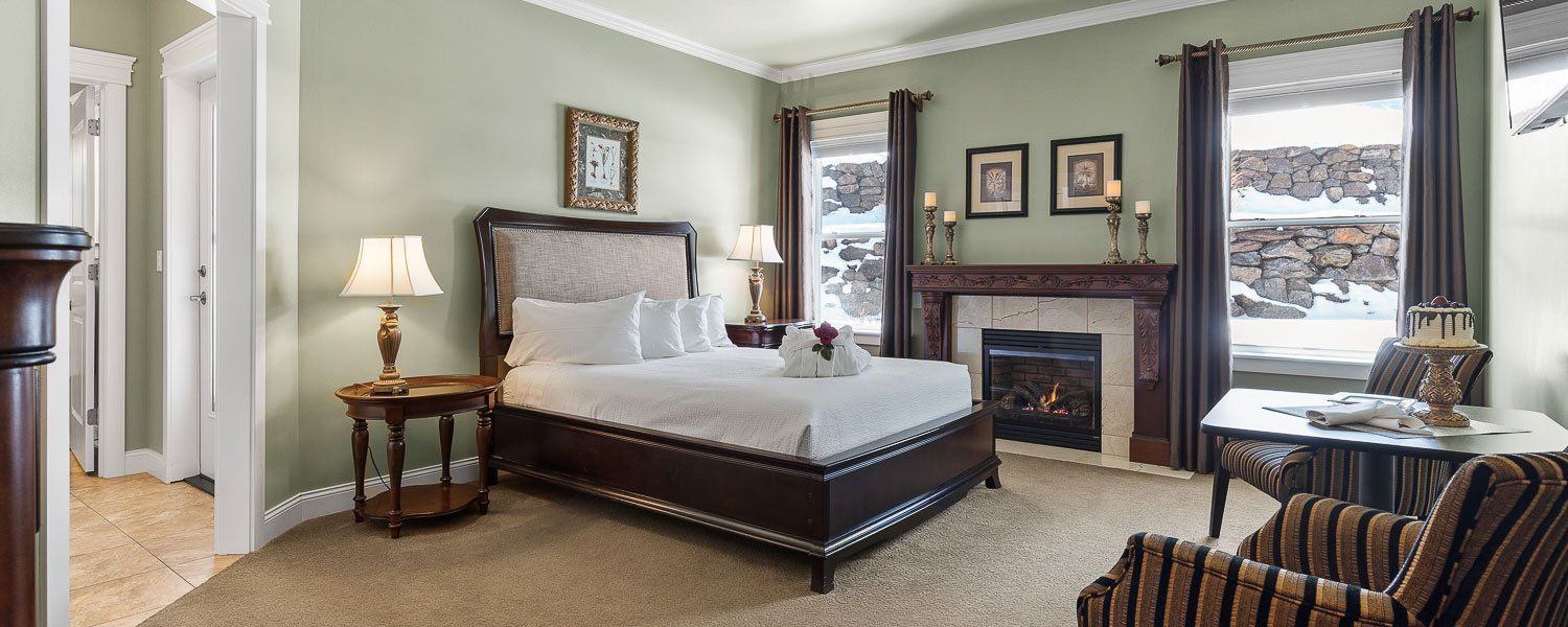 A bedroom with a bed , chair , table and fireplace.