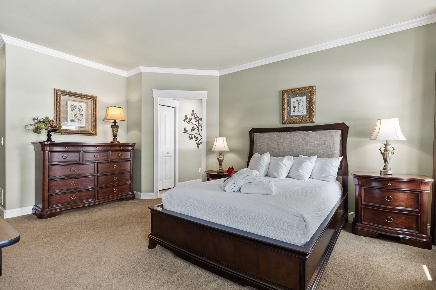 A bedroom with a bed , dresser , nightstand and lamps.