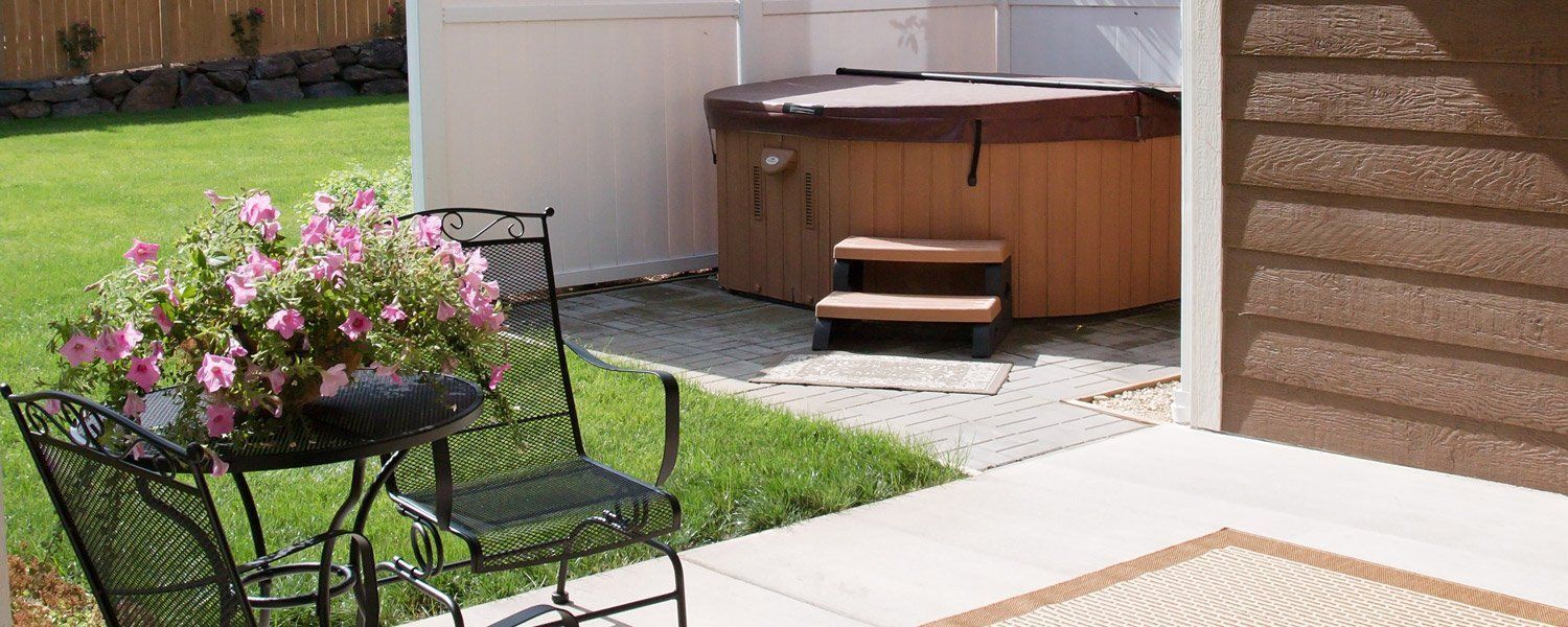 A hot tub is sitting in the backyard next to a table and chairs.
