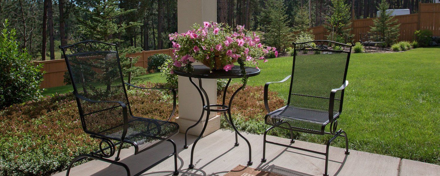A table and chairs on a patio with flowers in the background